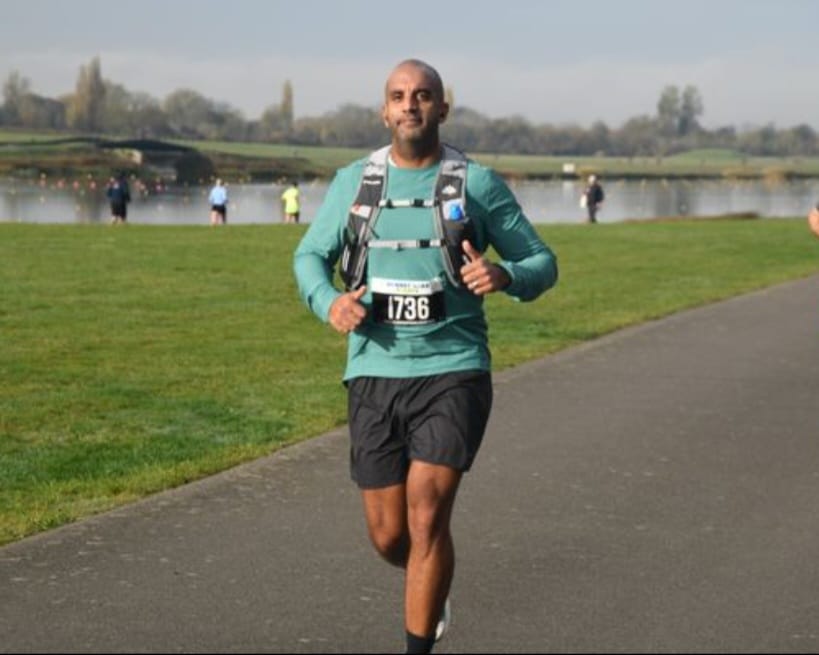 Runner in teal top with race bib at a riverside parkrun